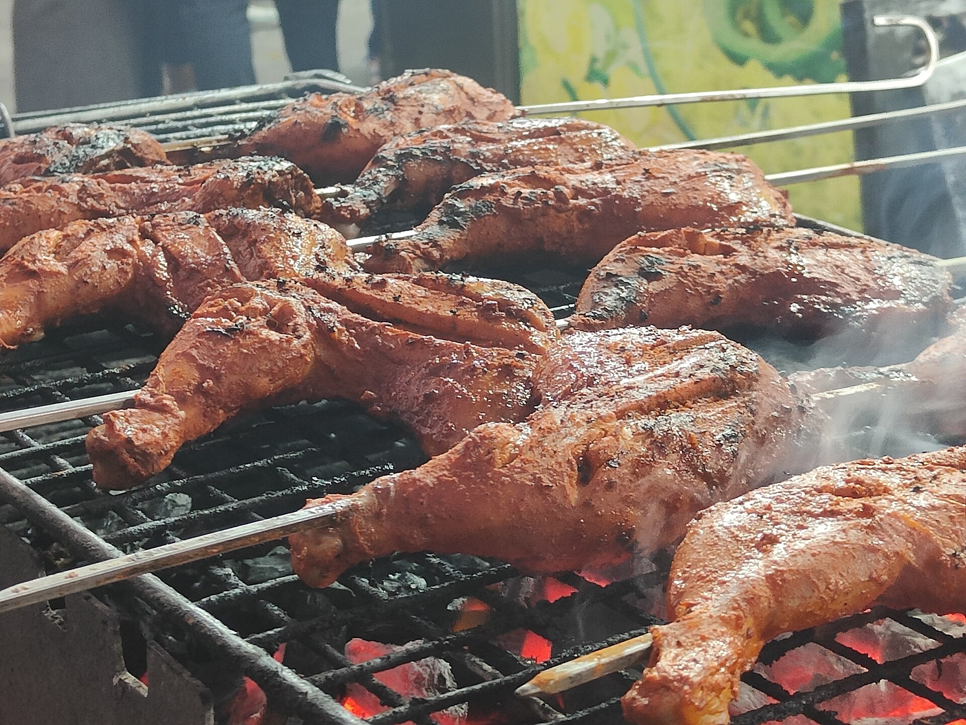 Tandoori chicken being grilled over flame.
